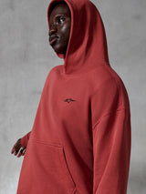 Alpinestars Essentials Ageless Hoodie, casual sportswear, Brick red, worn by a model with hood up, featuring a small black embroidered logo, soft fleece texture, relaxed fit streetwear