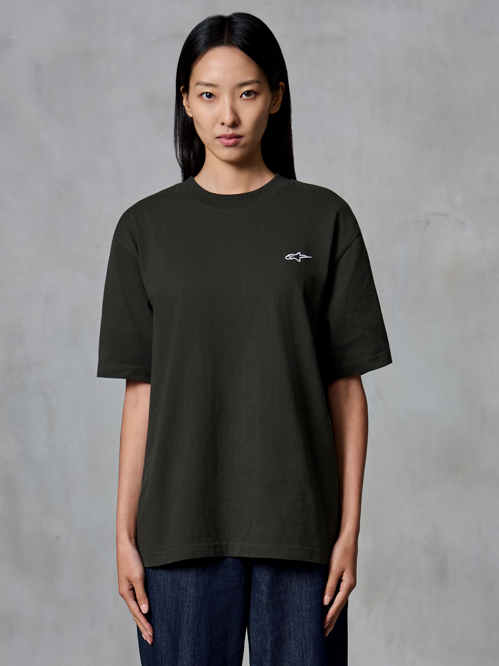 Alpinestars Essentials Ageless SS Tee, Short Sleeve T-Shirt, Off Black, worn by a female model, relaxed fit with a small white Alpinestars logo on the left chest, casual lifestyle apparel