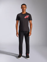 Male model wearing Alpinestars Shaded CSF Tee, Short Sleeve T-Shirt in Black, featuring a red slanted gradient foil Astars logo on the chest, styled with black pants and sneakers, casual motorsport streetwear