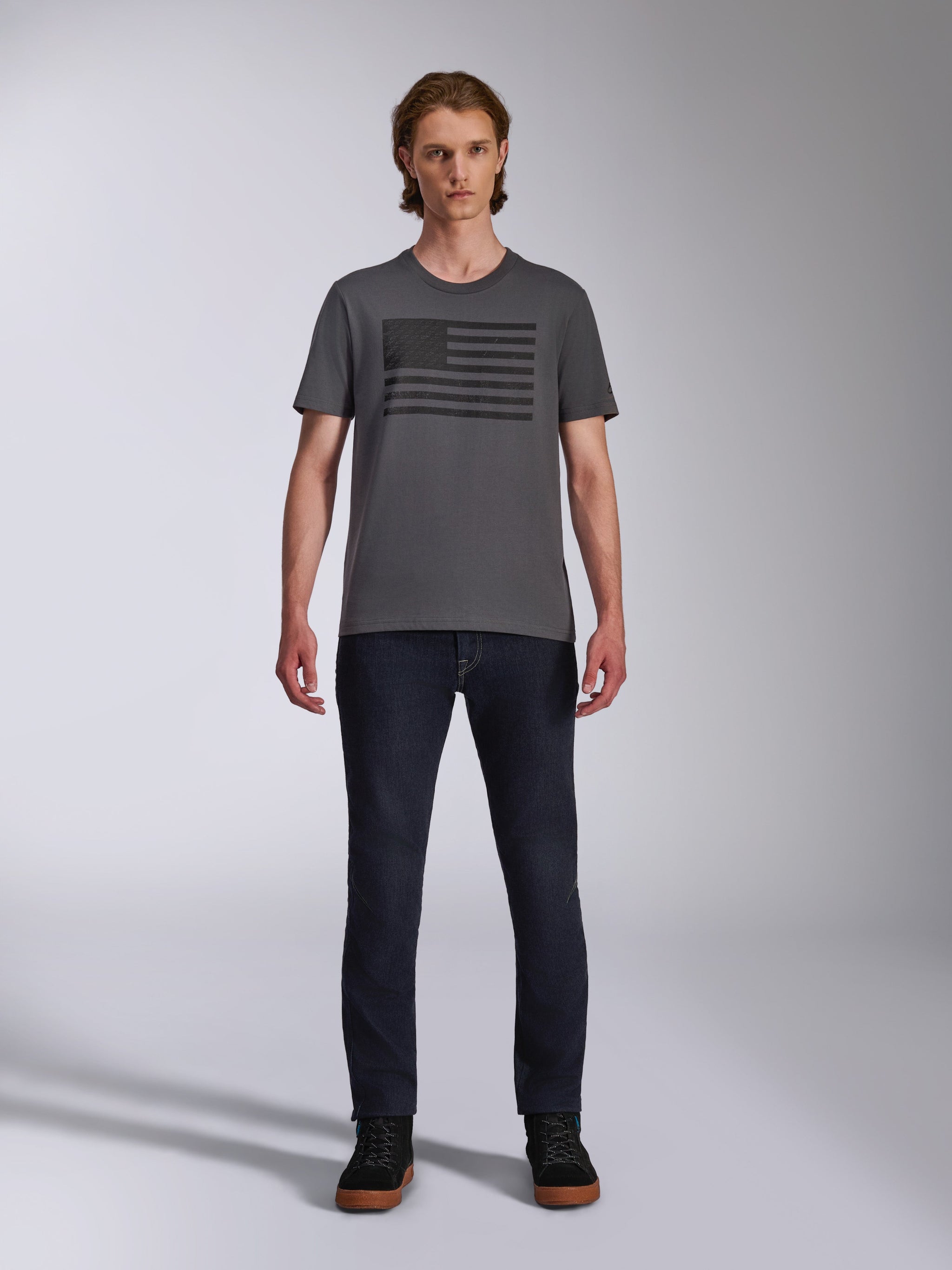 Alpinestars Waving CSF Tee, Short Sleeve T-Shirt, Charcoal Gray, Black Blaze 2.0 flag-style logo graphic, Casual Motorsport Streetwear, worn with dark denim jeans