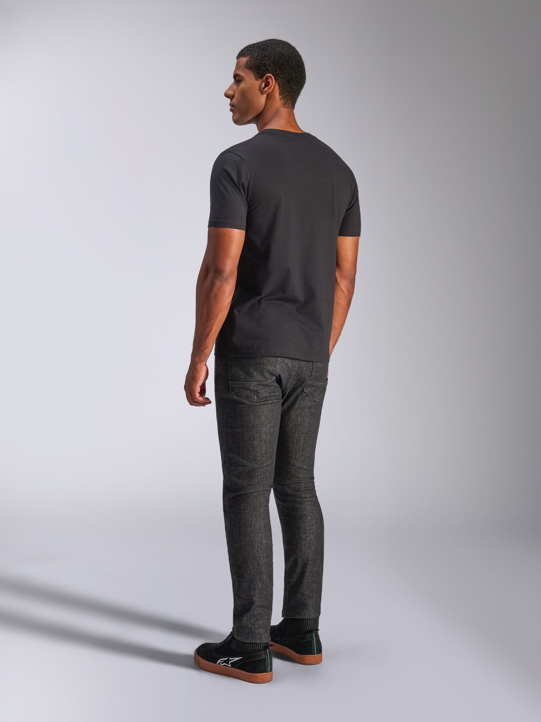 Alpinestars Tech Boot CSF Tee, Short Sleeve T-Shirt, Black, rear view on model, worn with dark gray denim pants and black sneakers, casual motorsport streetwear