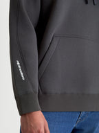 Alpinestars Prelude Oversized Hoodie, Sportswear Fleece Pullover in Charcoal Gray, detail shot showing the white puff-print logo on the sleeve, decorative seaming, and ribbed cuff and hem.