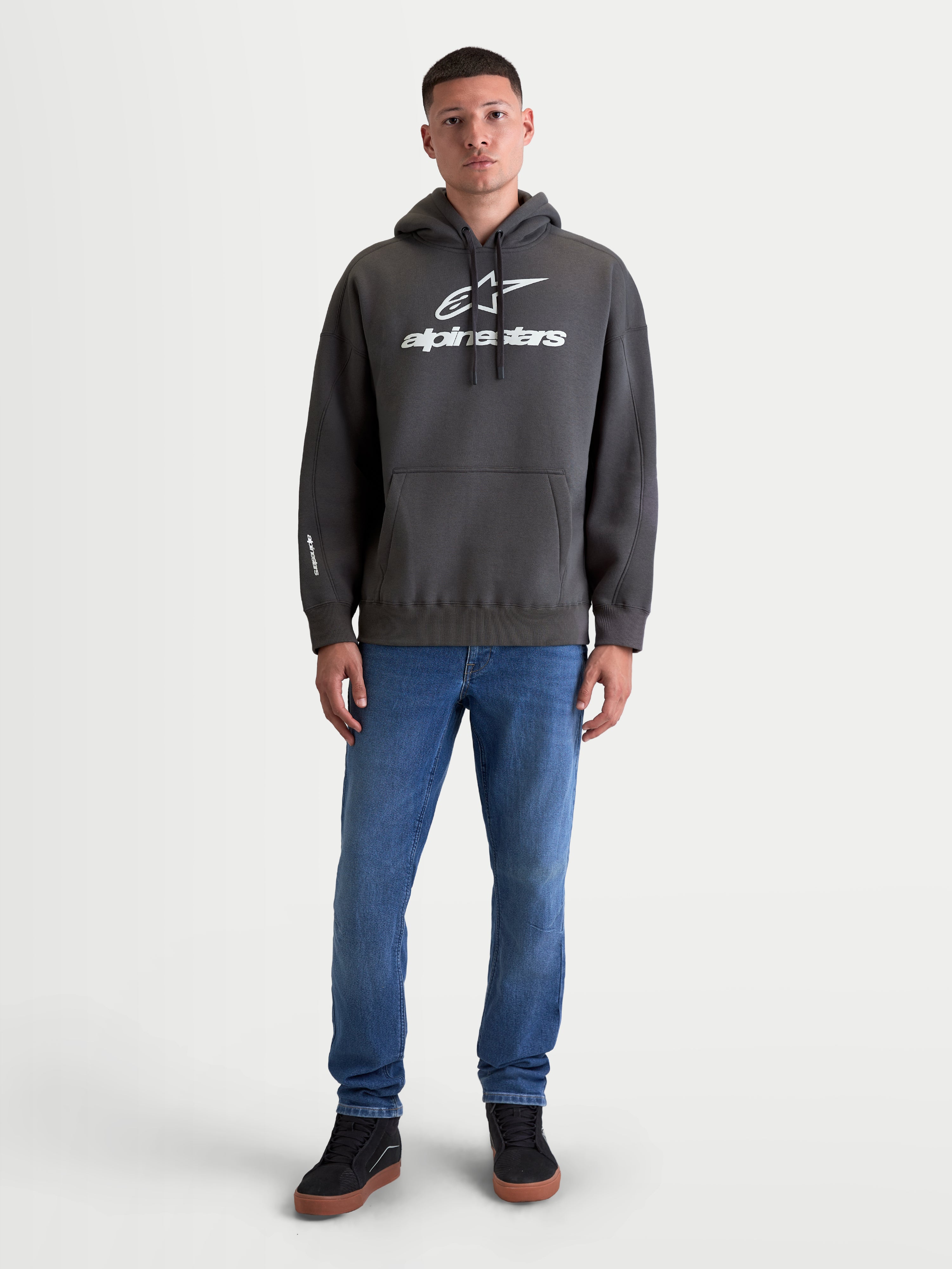 Alpinestars Prelude Oversized Hoodie, Men's and Women's Sportswear Fleece Pullover, Charcoal Gray, featuring a relaxed oversized fit, kangaroo pocket, and puff-print logos on the chest and sleeve, shown on model for casual everyday wear.
