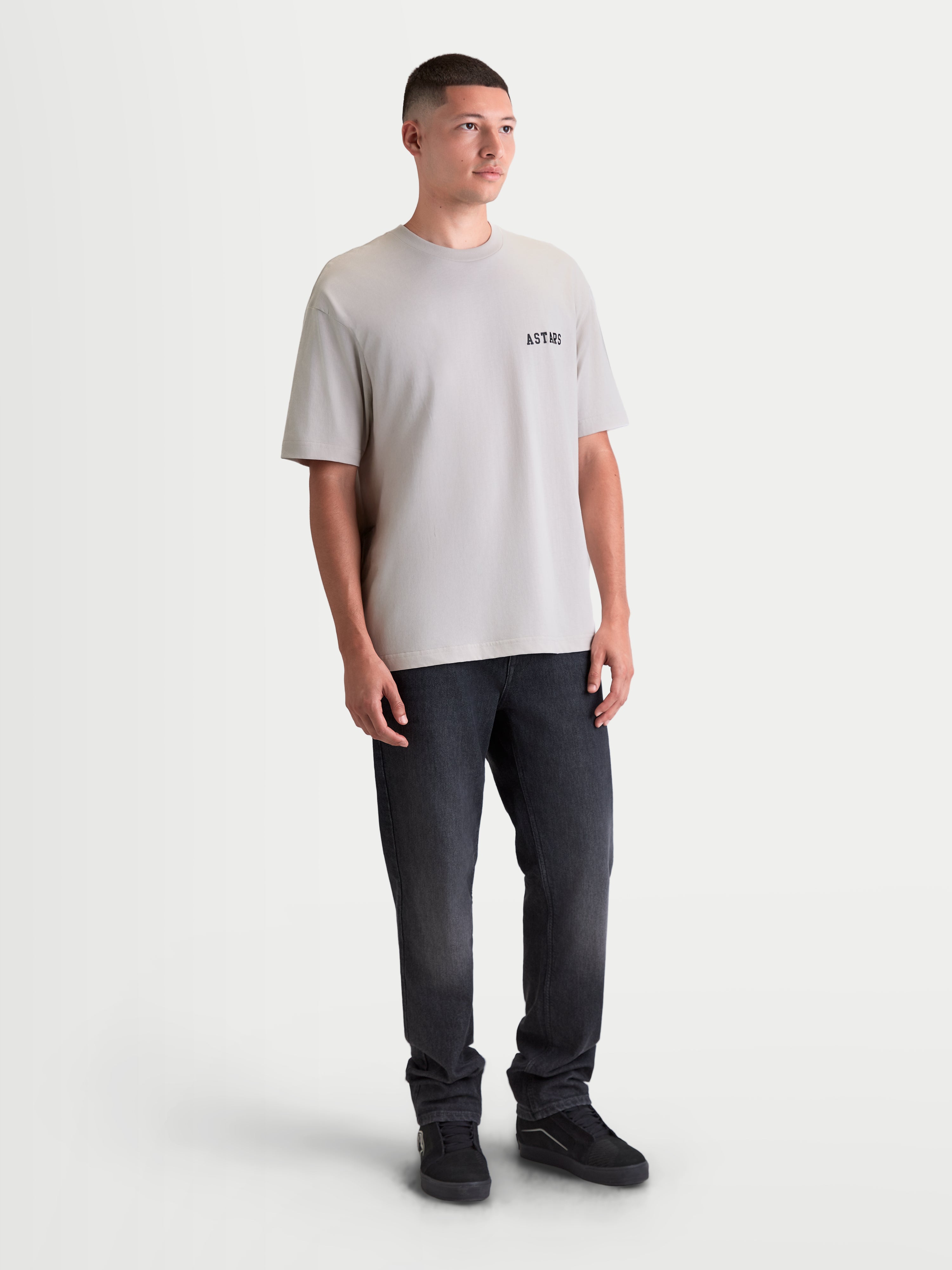 Alpinestars Latitude Oversized CSF Tee, Short Sleeve Sportswear T-Shirt on model, Cement Gray, featuring a relaxed oversized fit with a black ASTARS wordmark graphic on the chest, 60/40 cotton-poly blend for everyday comfort.
