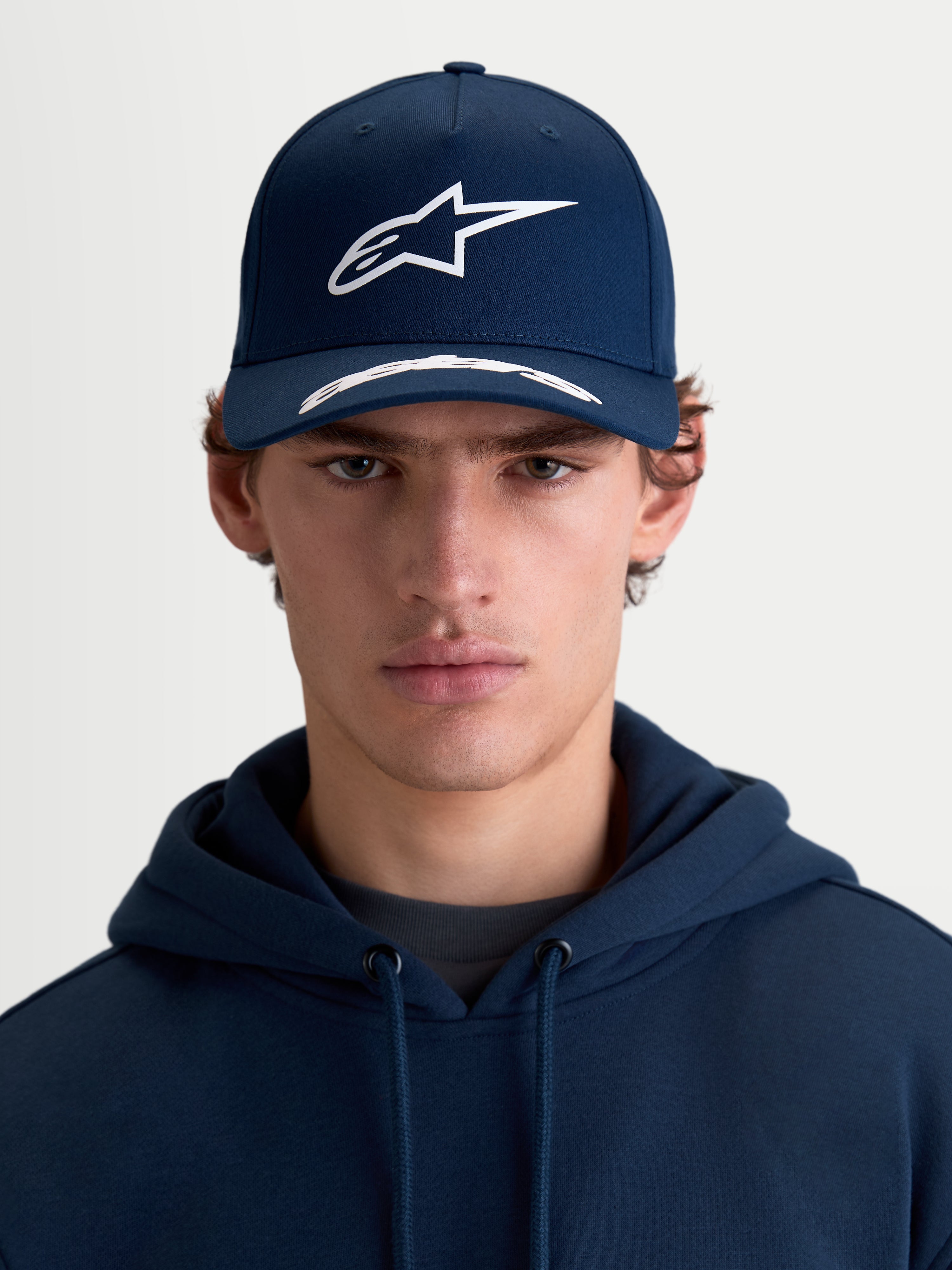 Alpinestars Arclight Hat, Sportswear Curved Bill Cap, Navy Blue and White, Front View on Model, featuring a Structured Crown, Textured Puff Print Astars Logo, and Premium Cotton Twill.