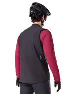 Alpinestars A-Dura Thermal Vest, Black, back view, worn over a maroon long-sleeve jersey with a black mountain bike helmet and gloves, lightweight insulated cycling gear for off-road riding