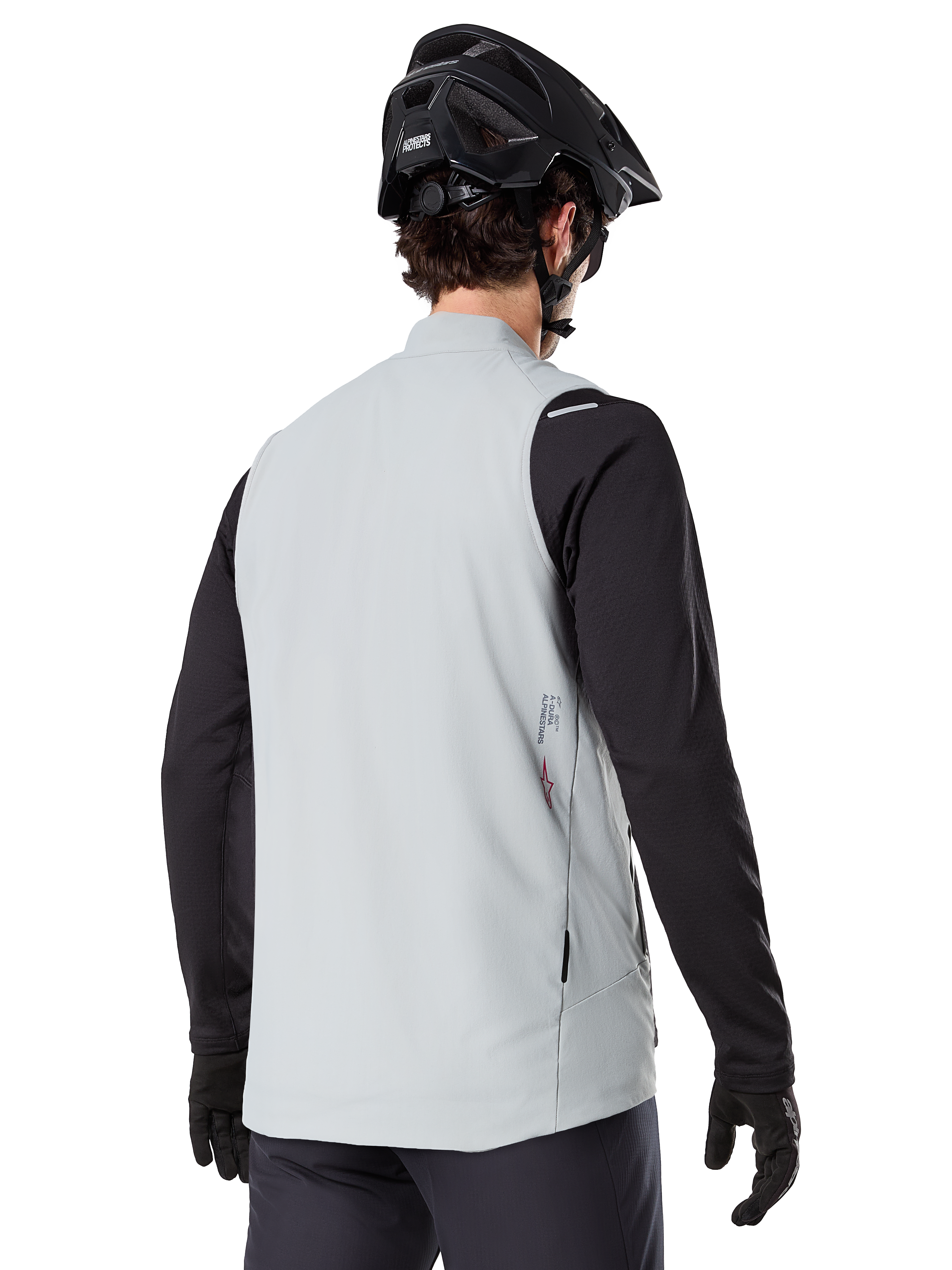 Alpinestars A-Dura Thermal Vest, Titanium Gray, rear view of model wearing a black long-sleeve jersey and MTB helmet, minimalist design with small red star logo on the back, lightweight insulated cycling gilet for off-road riding