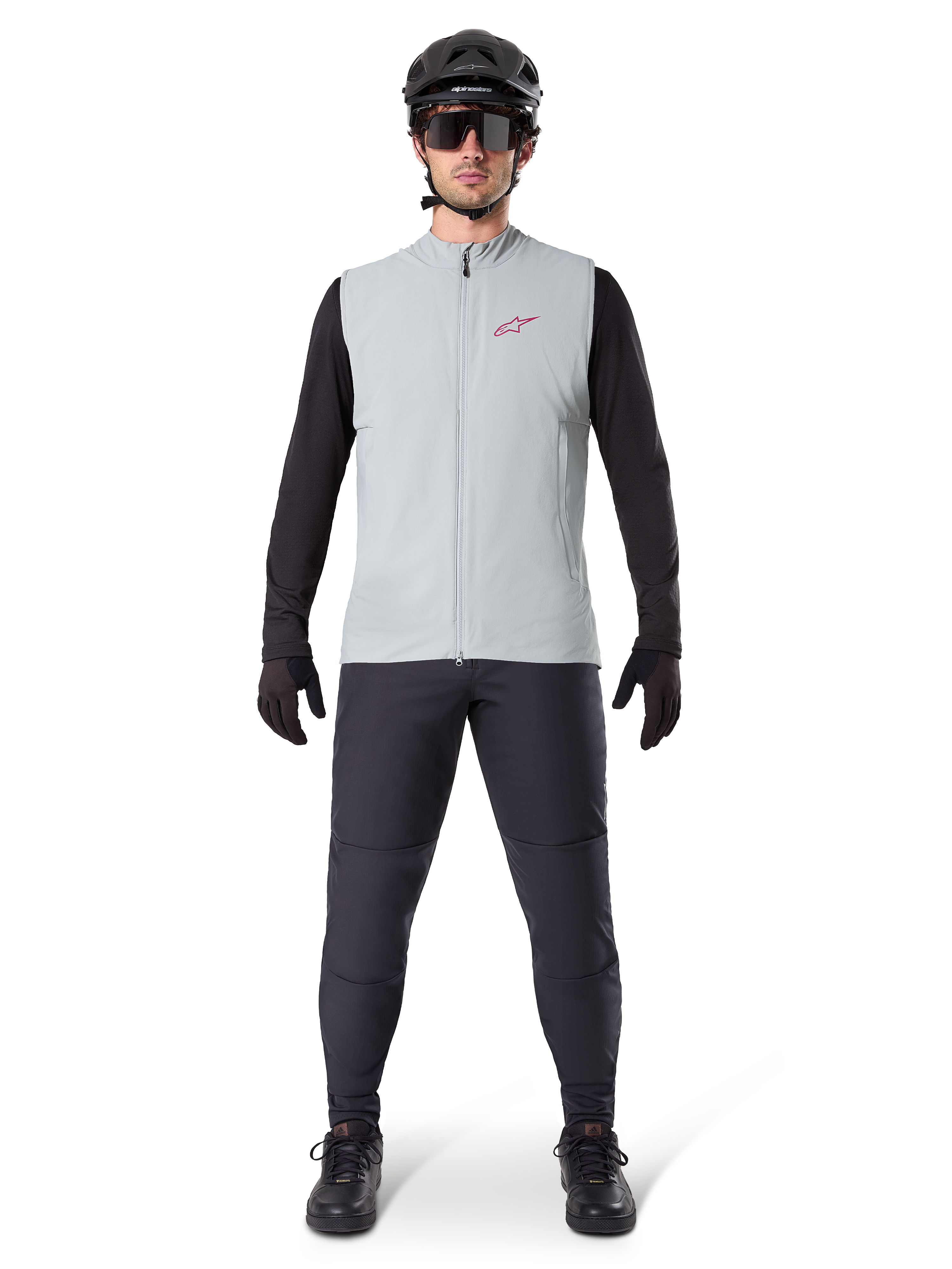 Alpinestars A-Dura Thermal Vest, cycling vest, Titanium Gray, worn with black long-sleeved jersey and black trousers, black helmet and sunglasses, featuring a red Alpinestars logo, lightweight thermal insulation for mountain biking