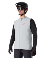 Alpinestars A-Dura Thermal Vest, Titanium Gray, cycling insulated vest, worn over a black long-sleeve shirt with a black mountain bike helmet and gloves, featuring a pink chest logo and vertical zippered side pockets