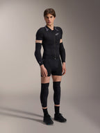 Male model wearing Alpinestars A-Motion Plasma Protection Jacket - Short Sleeve, Black Camo with gray patterned shoulders, central front zipper and white chest logo, worn with black arm and knee protectors, technical MTB protective gear for off-road riding.