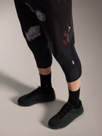 Alpinestars A-Dura Ride Shorts in Black Camo, durable MTB gear with orange logo, worn with knee guards and cycling shoes.