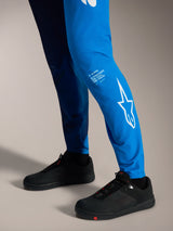 Faded Bright Blue A-Supra Elite Pants featuring white Astars branding on the lower leg and black MTB shoes.