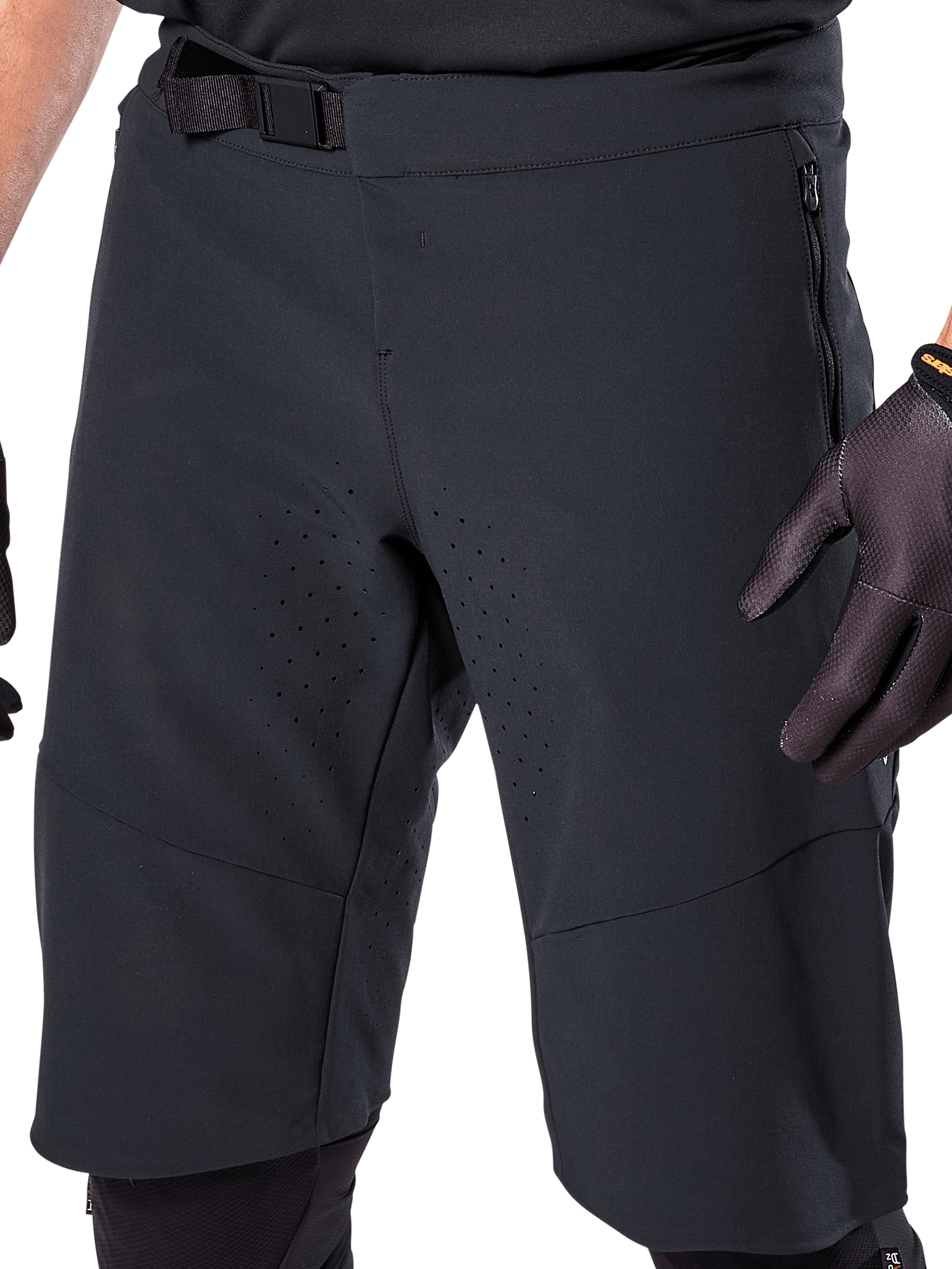Alpinestars A-Aria Elite Shorts in Black, close-up view of the waist and thigh area, featuring magnetic buckle closure, zippered pockets, and laser-cut ventilation perforations, worn with black cycling gloves for mountain biking.