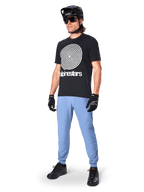 Alpinestars A-Dura Pants, MTB Pants, Infinity Blue, worn with black graphic t-shirt featuring white spiral logo, black helmet, sunglasses, and black gloves, professional mountain bike gear