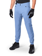 Alpinestars A-Dura Pants, Infinity Blue MTB Cycling Pants, featuring double snap front closure and zippered pockets, worn with black gloves and black shoes, durable 2-way stretch textile for off-road riding