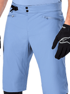 Alpinestars A-Dura Shorts, Infinity Blue mountain bike shorts, close-up of the waist featuring double snap closure, adjustable side cinch, and zippered mesh-lined pockets, worn with a black Alpinestars glove