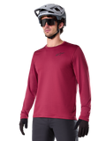 Alpinestars A-Dura Thermal Jersey, Long-Sleeve Mountain Biking Jersey, Burgundy Red, featuring insulated fleece lining and small black chest logo, worn with a gray helmet, black sunglasses, and black gloves, designed for cold-weather cycling