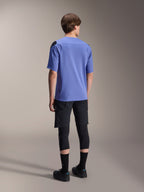 Alpinestars A-Aria Elite Shorts, Mountain Bike Shorts, Black Titanium, rear view worn with a lavender short-sleeve jersey, black knee guards, and black cycling shoes, athletic MTB gear setup.