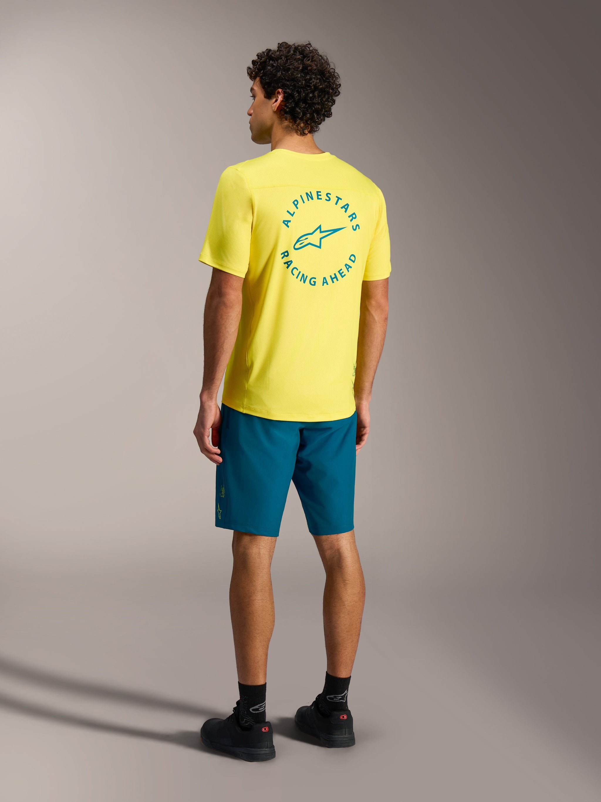 Alpinestars A-Dura Ride Shorts in blue green with a yellow jersey, rear view of mountain bike performance gear.