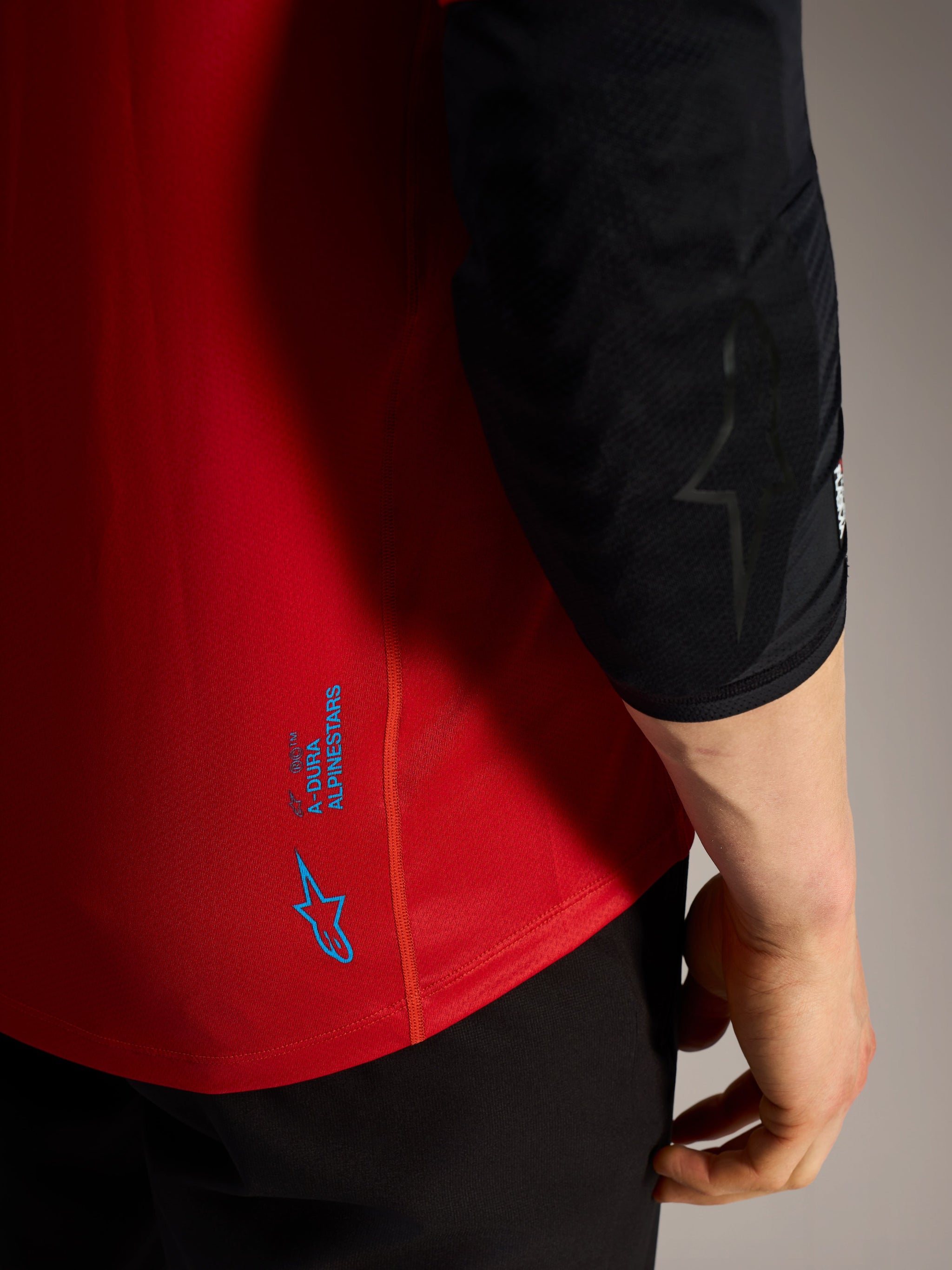 Red A-Dura Ride Short Sleeve Jersey detail with blue Alpinestars logos and technical performance fabric for MTB.