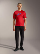 Red Alpinestars A-Dura Ride Short Sleeve Jersey with blue logo, styled with black pants for a casual MTB look.