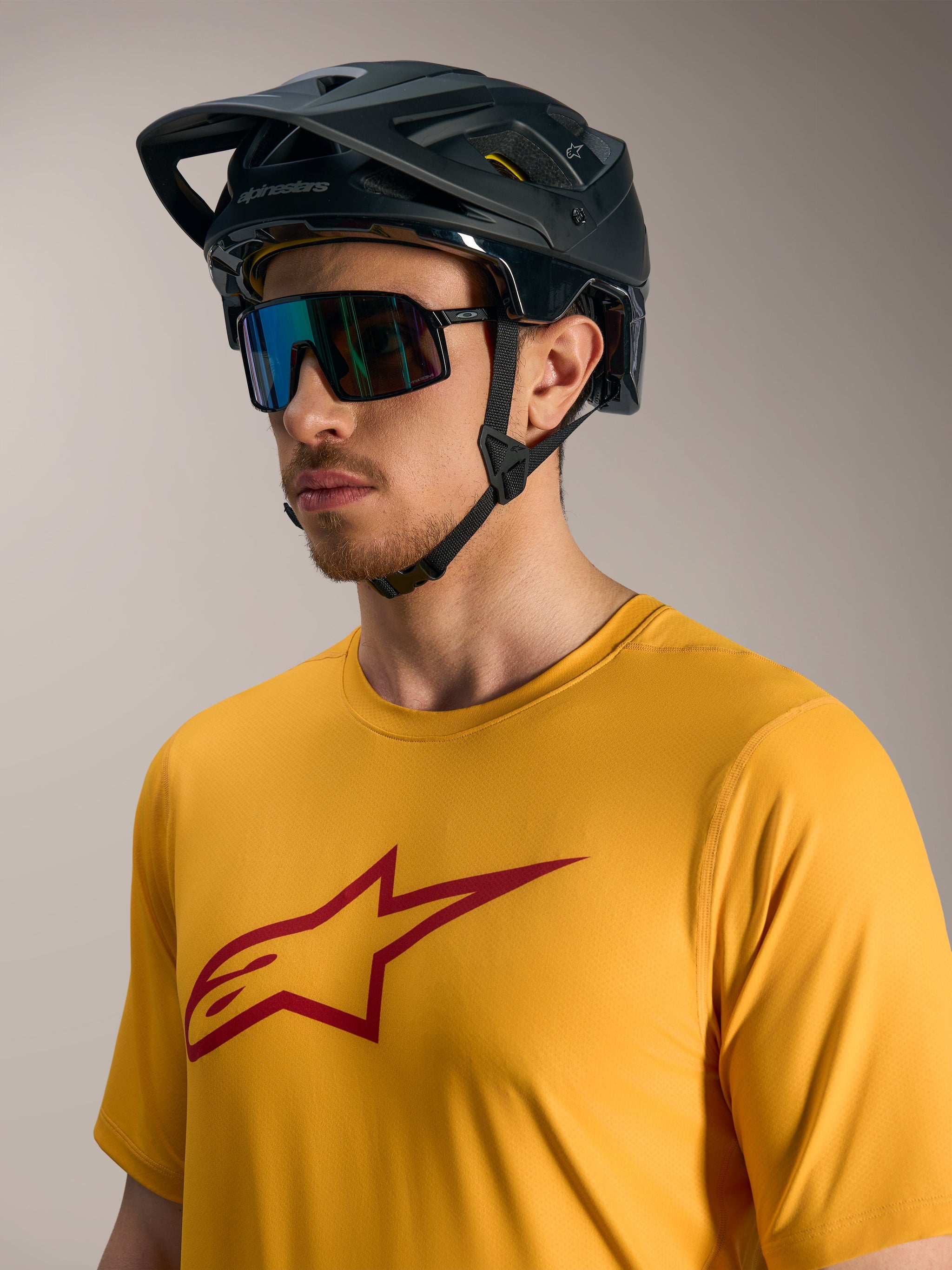 Orange A-Dura Ride Short Sleeve Jersey with red Astars logo, paired with a black MTB helmet and performance sunglasses.