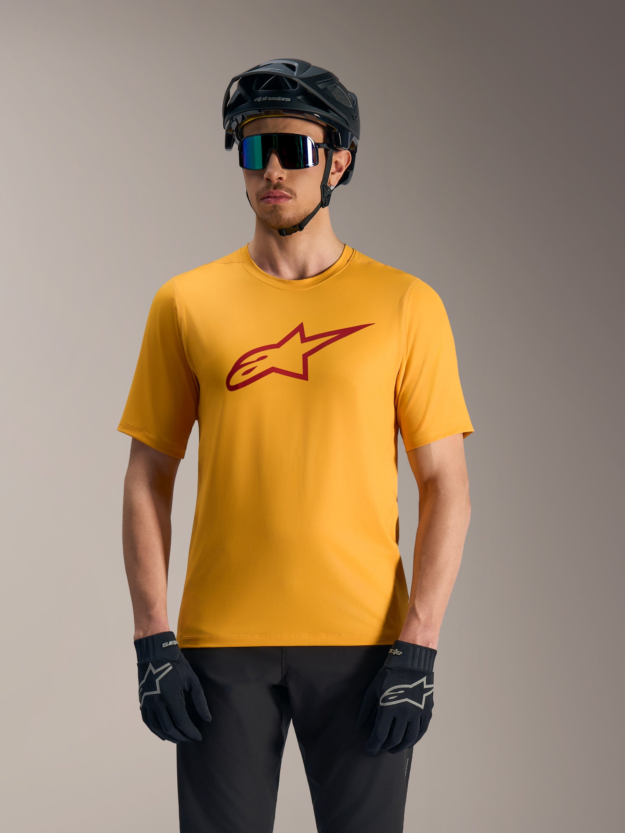 Orange A-Dura Ride Short Sleeve Jersey featuring a red Astars logo, styled with a mountain bike helmet and gloves.