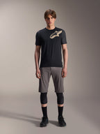 Alpinestars A-Dura Lipan Short Sleeve Jersey, Black with grey marl sleeves and tan Astars chest logo, worn by a male model with grey mountain bike shorts and black knee guards, performance MTB riding gear.