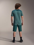 Alpinestars A-Dura Lipan Short Sleeve Jersey in Silver Pine, back view showing the textured jacquard shoulder panels and drop tail hem, worn with matching dark green mountain bike shorts and black footwear.