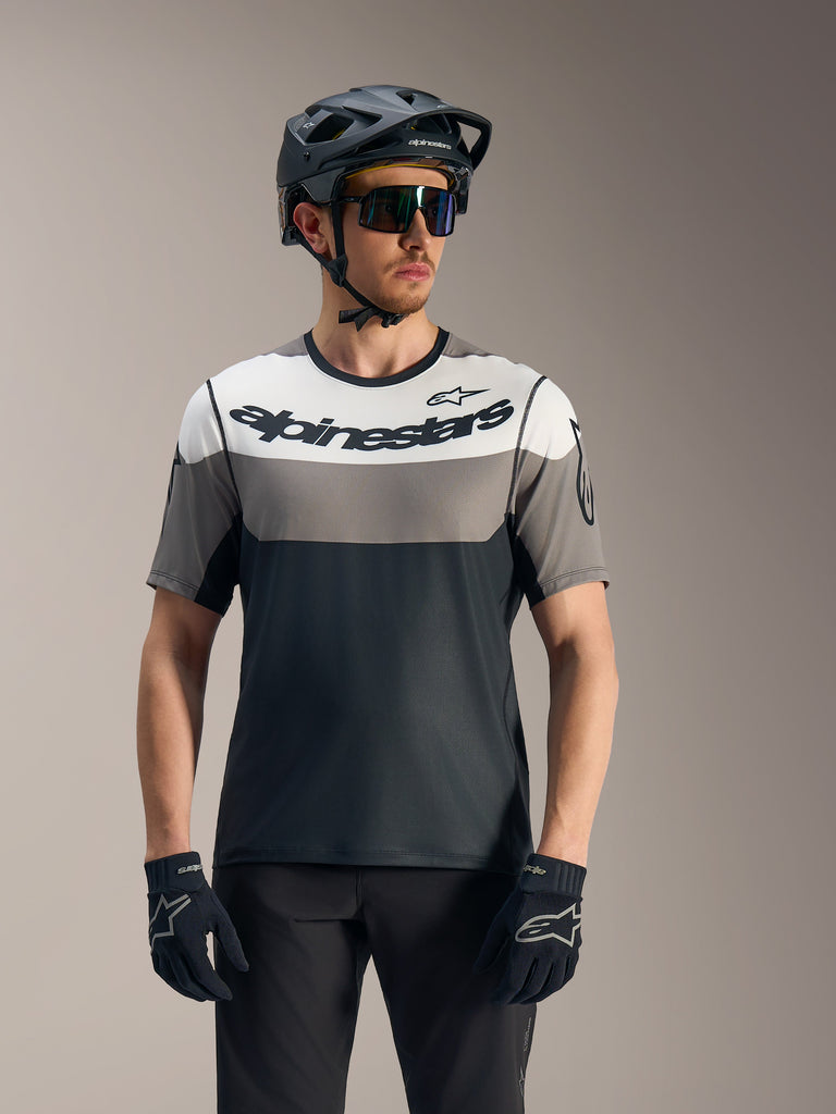 A-Dura Race Short Sleeve Jersey in grey and black with bold Alpinestars logo, shown with MTB helmet and eyewear.
