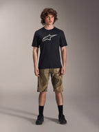Alpinestars A-Dura Astar Short Sleeve Jersey, Black with large white Astars logo on the chest, worn by a model with camouflage MTB shorts and black cycling shoes, casual mountain bike apparel.