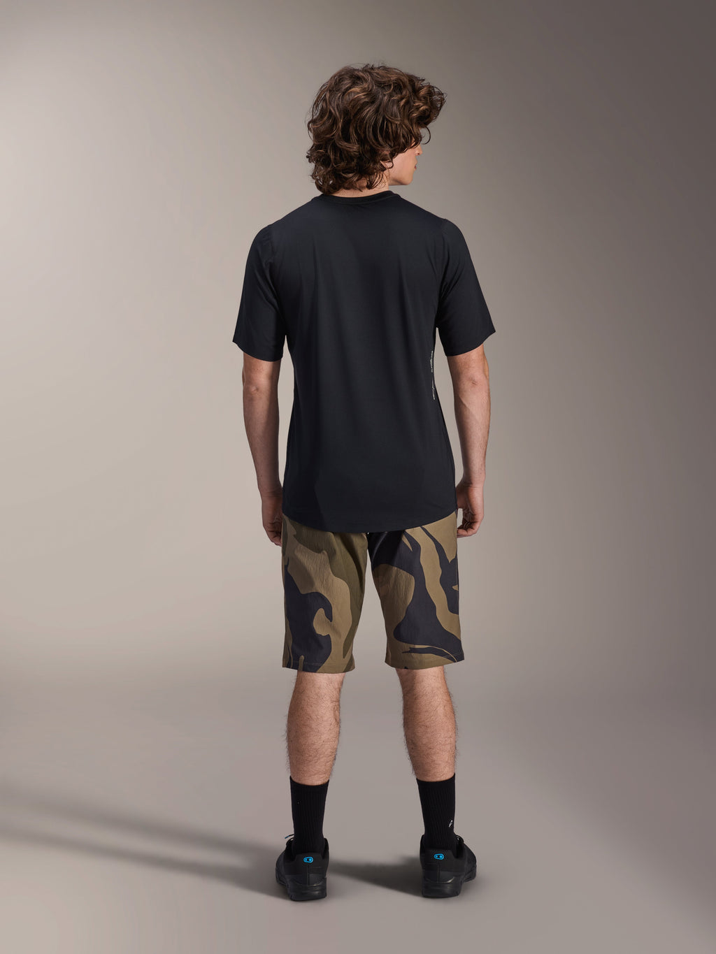 Alpinestars A-Dura Astar Short Sleeve Jersey, Black, back view on a model paired with camouflage patterned MTB shorts and black footwear, casual technical mountain bike apparel