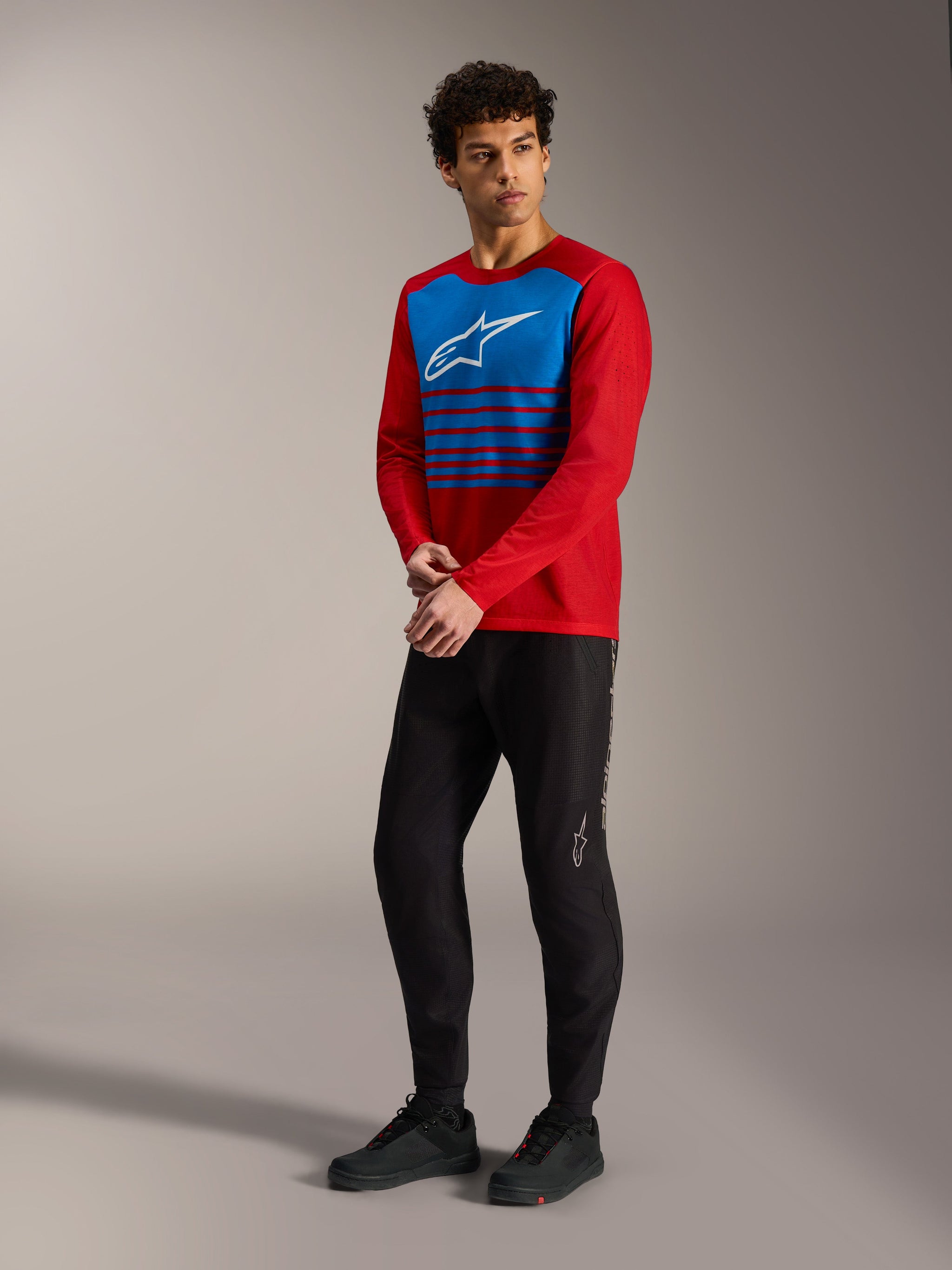Red A-Dura Elite Long Sleeve Jersey 2.0 with blue striped chest panel and white logo, paired with black MTB pants.