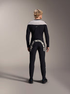 Man seen from behind wearing Alpinestars A-Supra Melt Long Sleeve Jersey in Black, light grey shoulder panel, paired with black MTB pants featuring a large Alpinestars logo across the rear, performance mountain bike kit