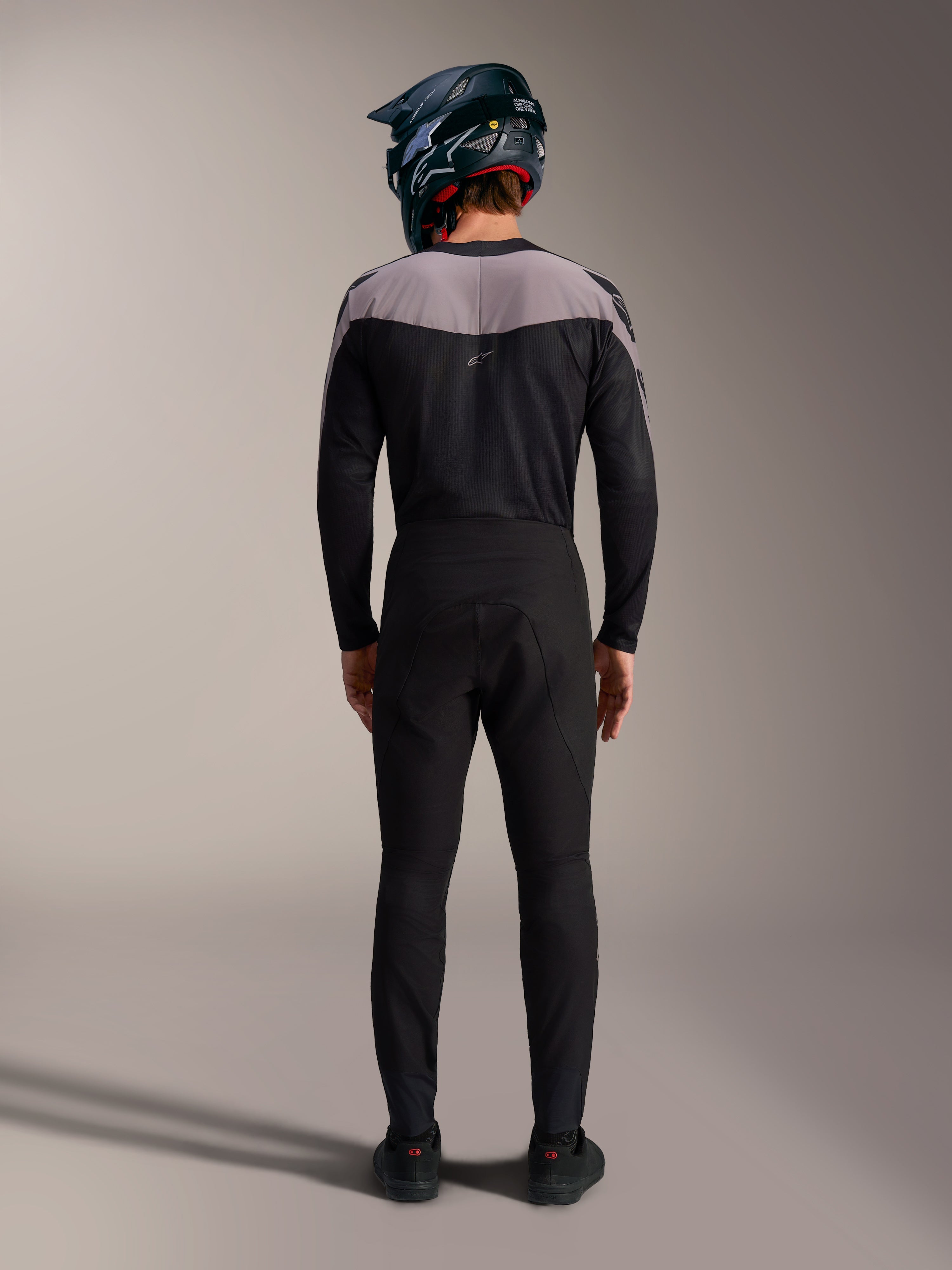 Alpinestars A-Supra Elite MTB kit in black, featuring performance pants and jersey with a full-face helmet, back view.
