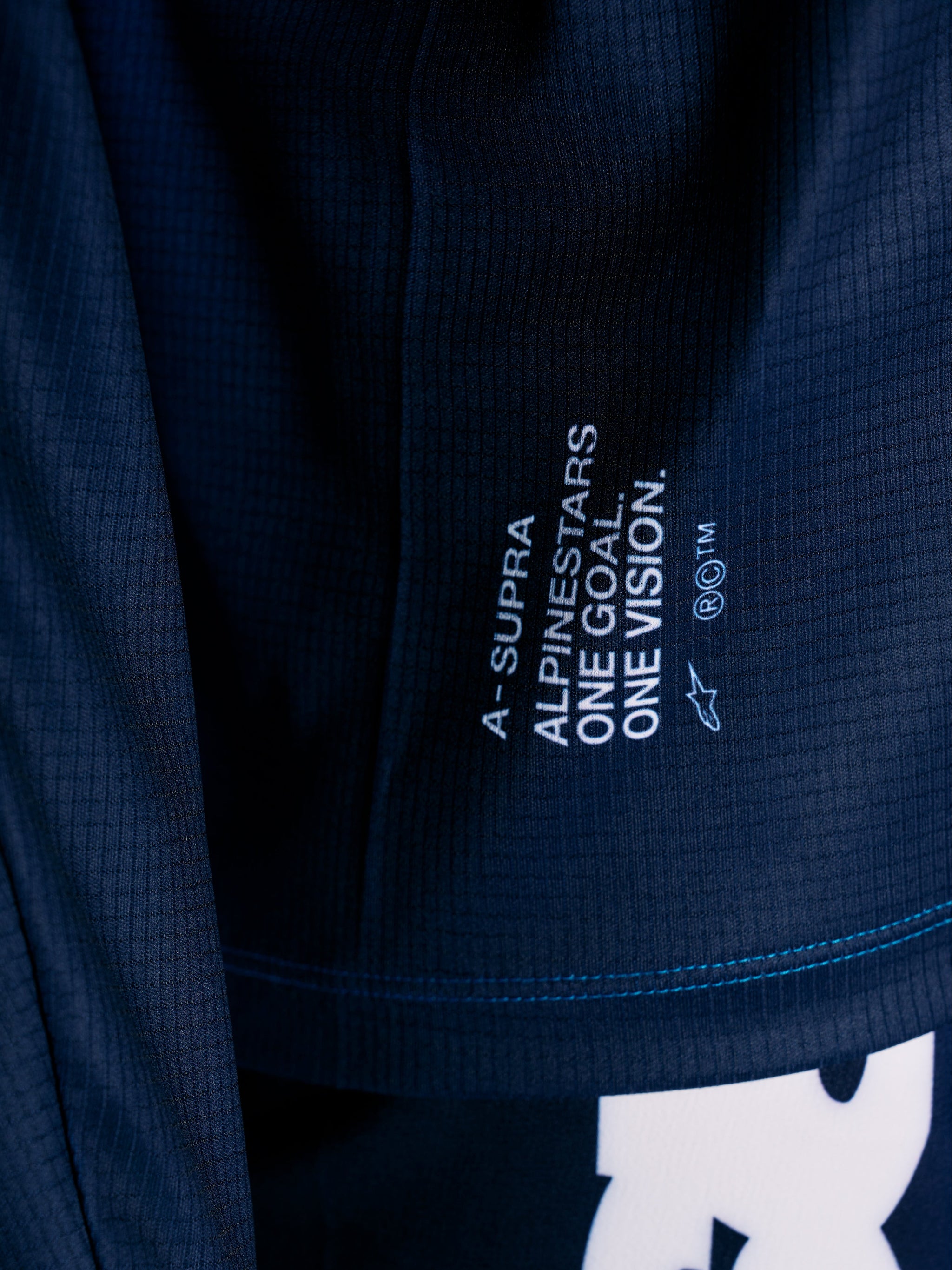 Blue A-Supra Elite MTB Jersey close-up, featuring micro-perforated fabric and the One Goal One Vision racing slogan.