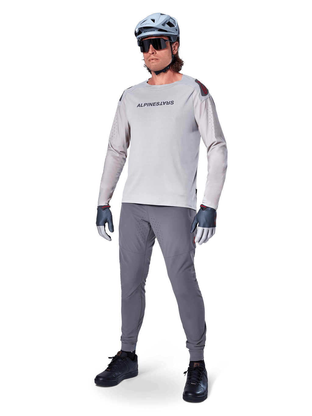 Alpinestars A-Aria Polartec Switch Jersey, Long Sleeve MTB Jersey, Light Gray, worn with dark gray mountain bike pants, helmet, and gloves, featuring laser-perforated sleeves and Alpinestars branding on the chest.