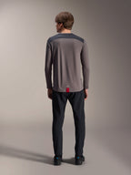 Alpinestars A-Dura Insert Astar Long Sleeve Jersey in Dark Gray, rear view, featuring charcoal shoulder panels and a red tag at the hem, worn with black pants and shoes, mountain bike performance apparel