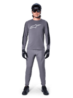 Alpinestars A-Dura Dri Astar Jersey, Long Sleeve MTB Jersey in Dark Gray, featuring a white chest logo and black sleeve panels, worn with matching gray pants, black helmet, sunglasses, and gloves for a complete off-road cycling outfit