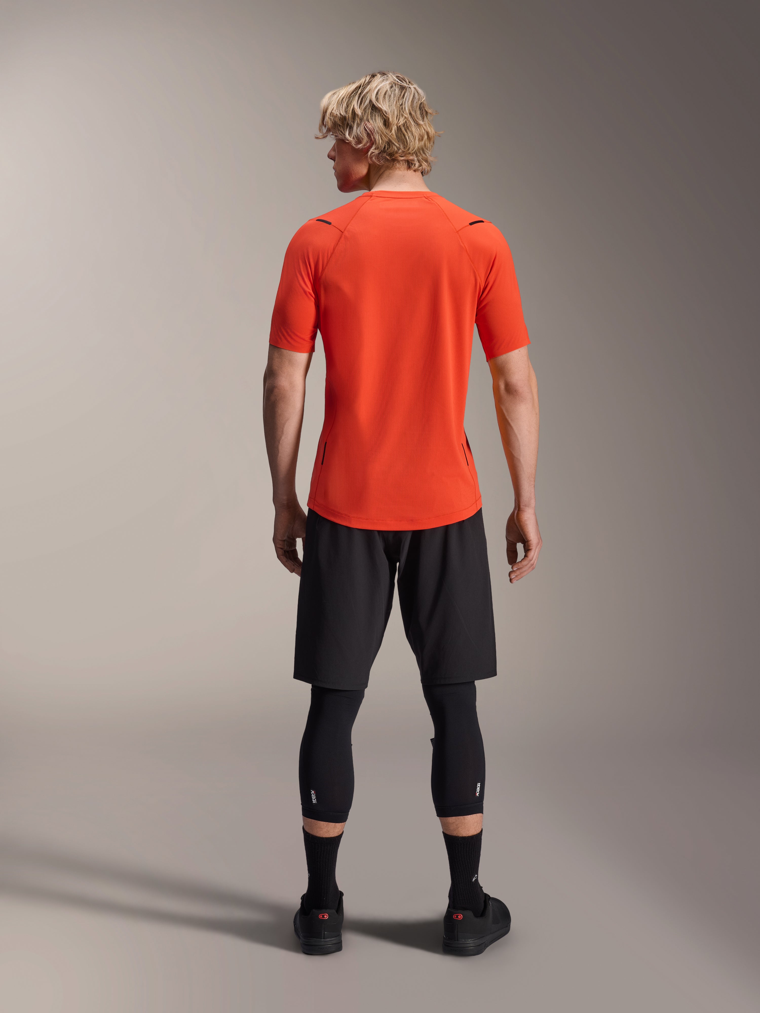 Alpinestars A-Aria Astar Jersey, Short Sleeve MTB Jersey, Spicy Orange, back view showing performance fit and longer drop tail, paired with black cycling shorts and leggings