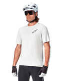 Alpinestars A-Aria Astar Short Sleeve Jersey, White Dove, worn by a cyclist with a white helmet and dark sunglasses, featuring a small black star logo on the chest, breathable performance gear for mountain biking