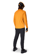 Mountain bike rider seen from behind wearing the Alpinestars A-Dura Rocker Long Sleeve Jersey in Dark Gold, black pants, orange and black helmet, and black shoes, coordinated performance MTB gear for trail riding