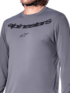 Alpinestars A-Dura Rocker Long Sleeve Jersey, Dark Gray, close-up of chest featuring black Alpinestars wordmark and star logo, jacquard poly-spandex material, performance mountain bike apparel