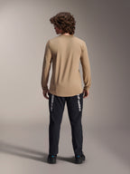 Alpinestars A-Dura Astar Long Sleeve Jersey, Light Brown, back view showing the longer drop tail, worn with black pants featuring Alpinestars branding, performance mountain bike apparel