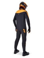 A-Supra Race Jersey - Long Sleeve, Black and Orange, rear view of a rider wearing matching MTB pants, orange and black helmet, and gloves, performance gear for mountain bike racing