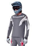 Alpinestars A-Supra Race Jersey - Long Sleeve, Dark Gray with white and red accents, racing-style graphics, worn with matching gray pants, blue full-face helmet, and white gloves, professional MTB and downhill racing gear