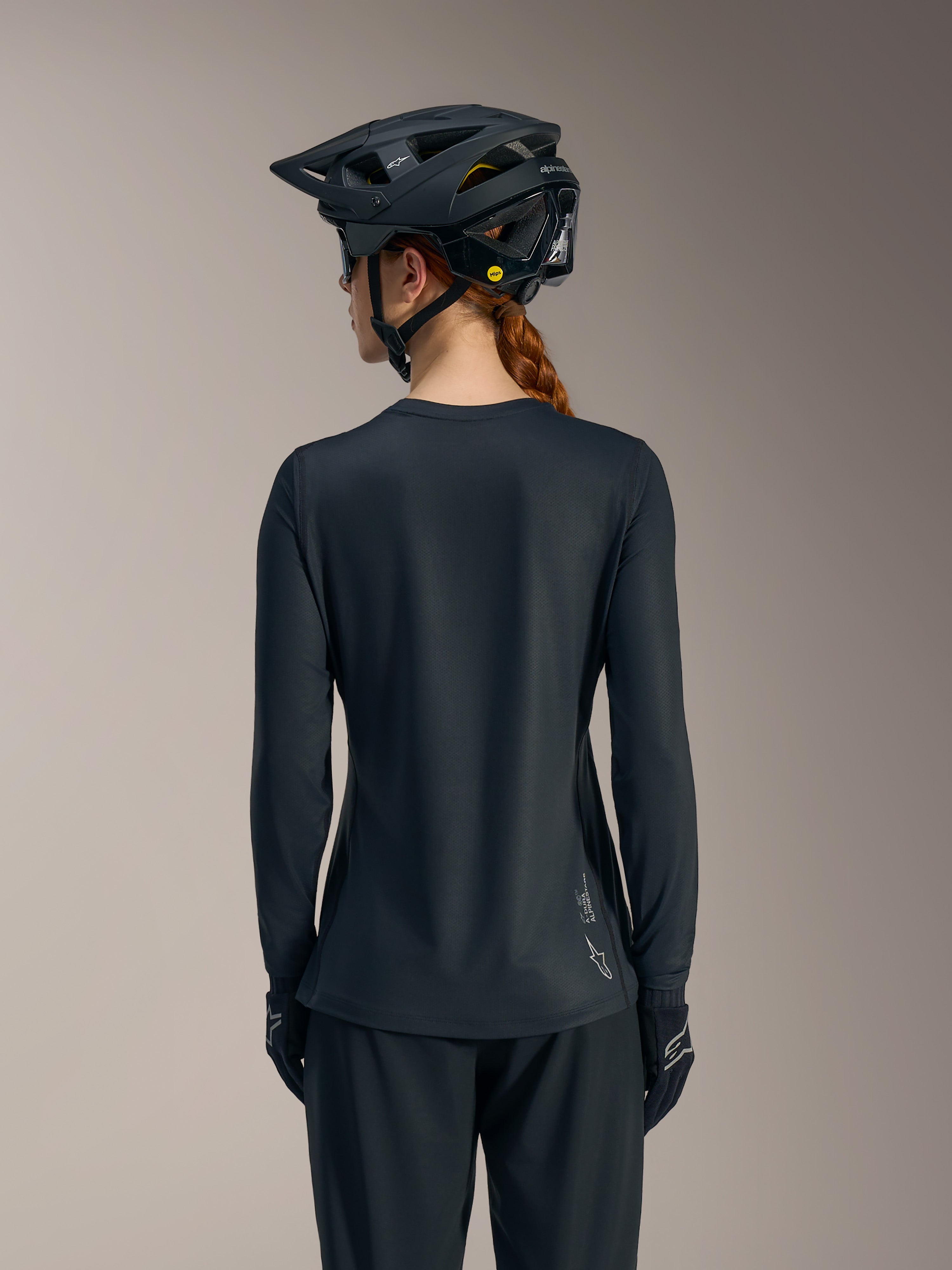 Black Stella A-Dura Ride Long Sleeve MTB Jersey back view, featuring subtle Alpinestars logo branding on the lower hem.