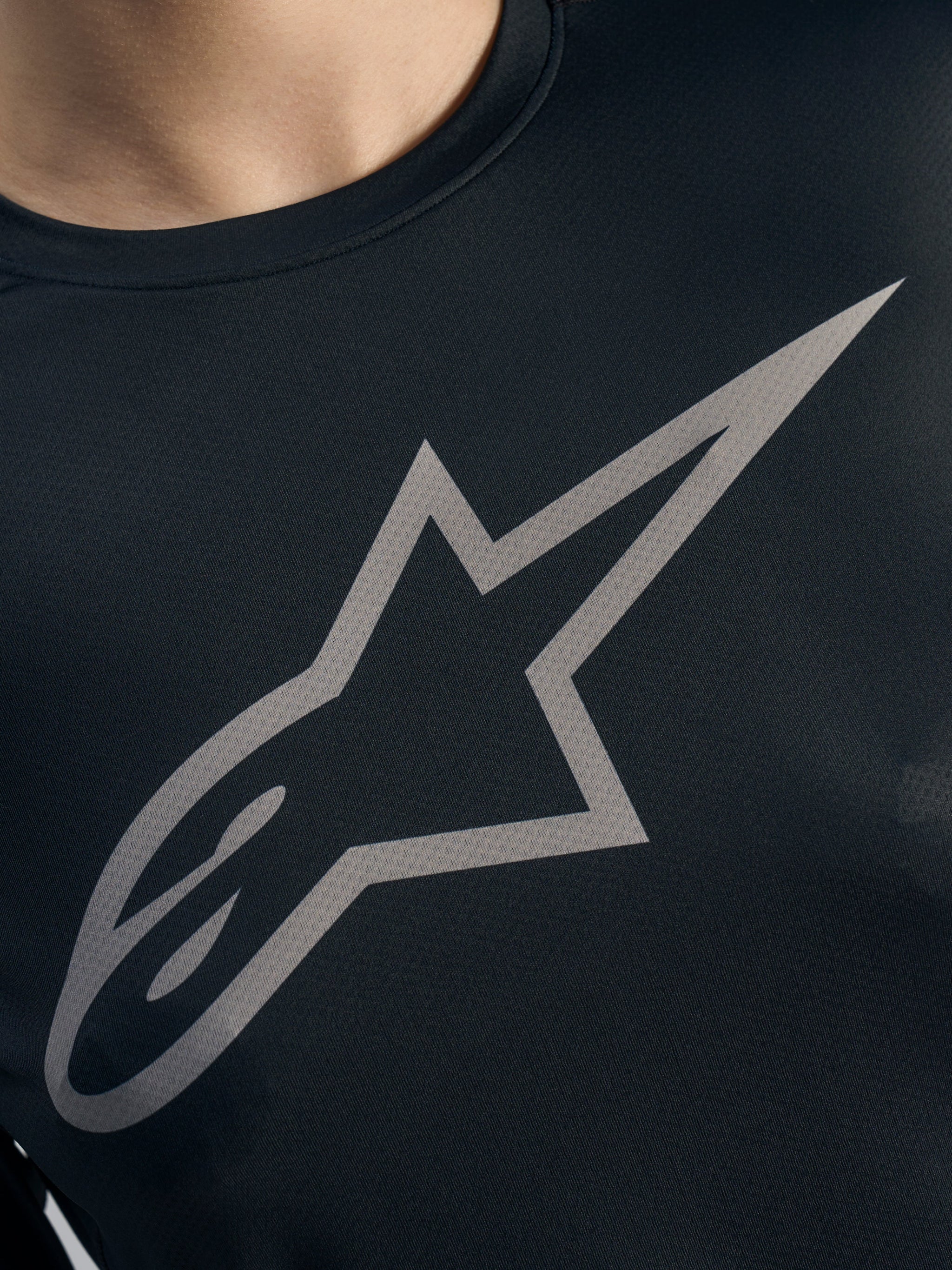 Grey Alpinestars logo detail on a black Stella A-Dura Ride Long Sleeve Jersey, featuring women's MTB jacquard fabric.