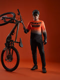 A-Dura ASTARS Long Sleeve Jersey 2.0 in orange-black gradient with bold chest logo, shown with full mountain bike gear.