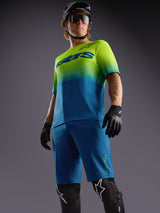 Alpinestars A-Dura Ride Shorts in blue paired with a gradient lime and blue jersey and protective MTB gear.